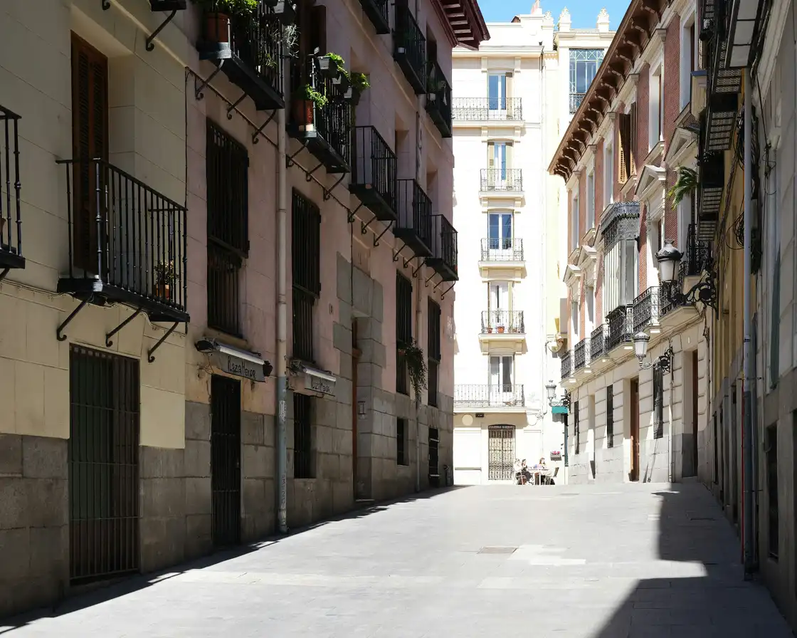 A sunlit street between traditional buildings in Madrid
